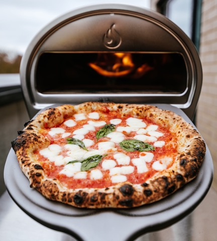 Gas pizzaovn hvor en pizza er taget ud ved hjælp af en pizzaspade